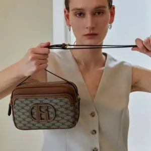 [헤지스](대전신세계)[HARIATO] H 레더 브라운 패치 시그니처 패턴 미니크로스백 HIWA6E520G2