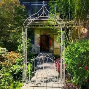 야외 정원 잔디밭 뒷마당에 있는 다양한 등산 식물을 위한 게이트가 금속 아치