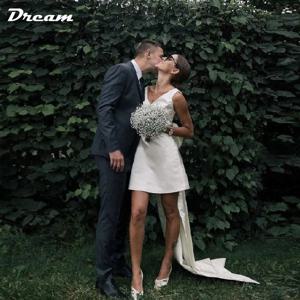 DREAM 맞춤 제작 숏 미니 새틴 브이넥 브라이덜 가운 큰 리본 오픈백 민소매 무릎 위 길이 웨딩 파티 드레스 2026 결혼식 피로연과 애프터파티에 어울리는 우아한 신부 드레스 세련된 여성 맞춤 예복 고급 새틴 광택과 시선을 끄는 대형 리본 오픈백과 슬림한 민소매 디자인이 돋보이며 무릎 위로 떨어지는 짧은 길이로 본식 2부, 피로연, 웨딩 파티와 촬영에 잘 어울리는 맞춤 여성 신부 의상